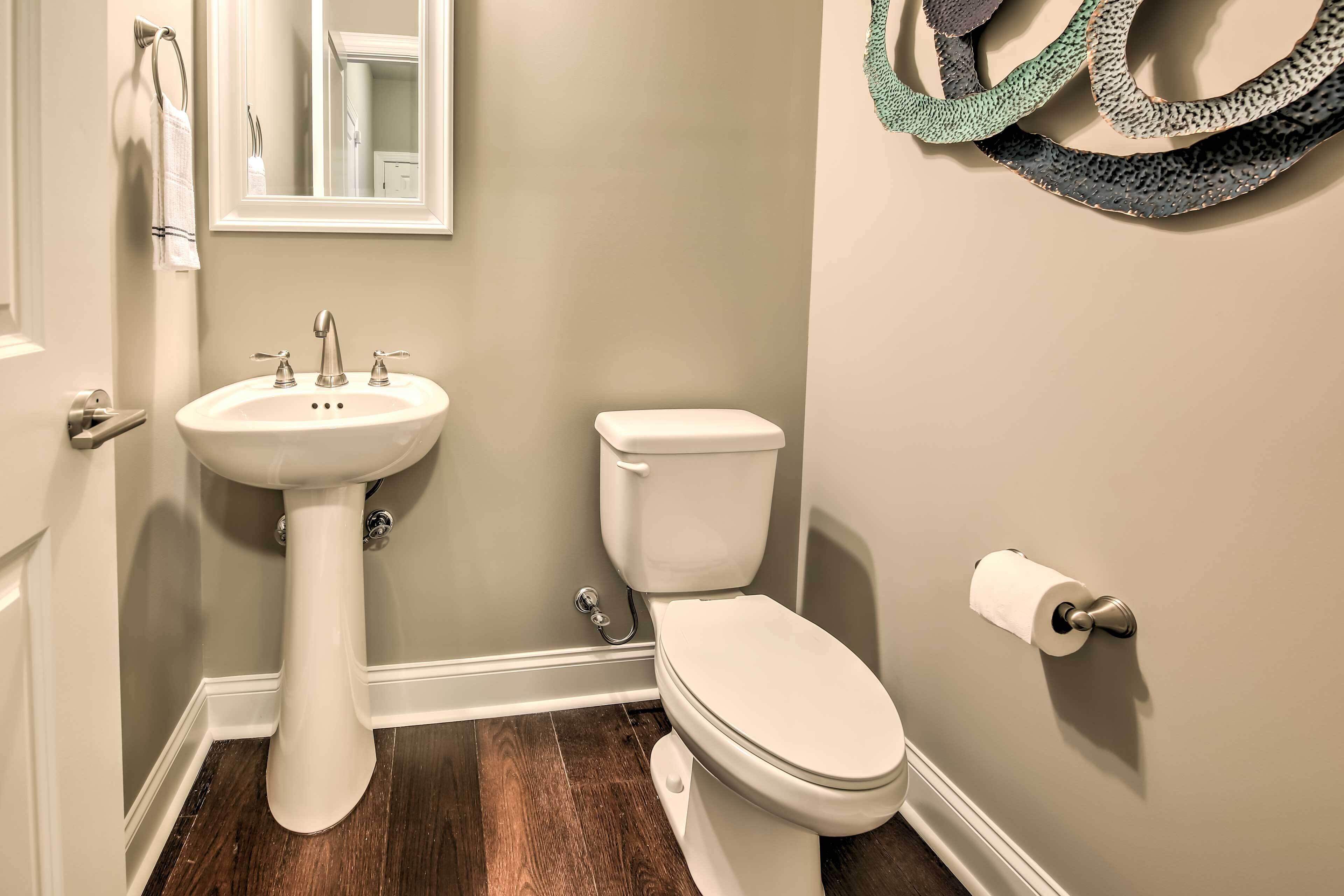 A bathroom with a pedestal sink, toilet, and a mirror.