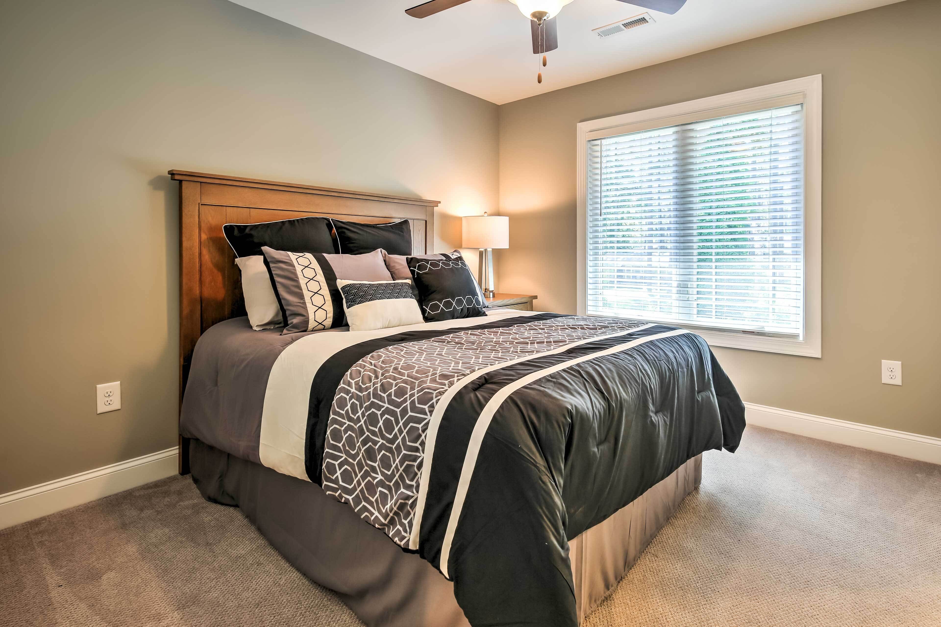 A bedroom with a bed, a nightstand, a lamp, and a window with blinds.