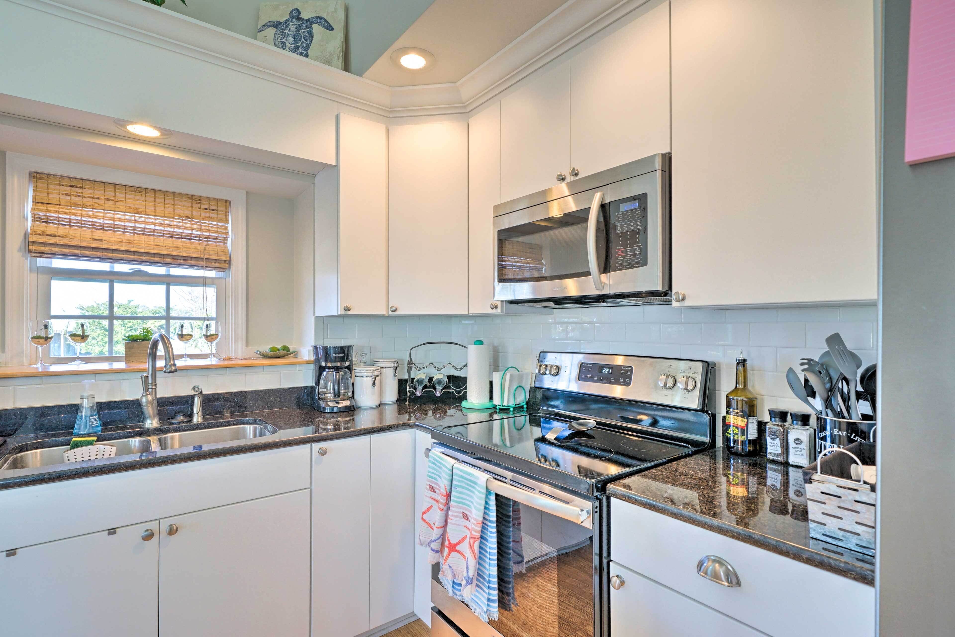 A modern kitchen with white cabinets, stainless steel appliances, a dishwasher, and a window with blinds.