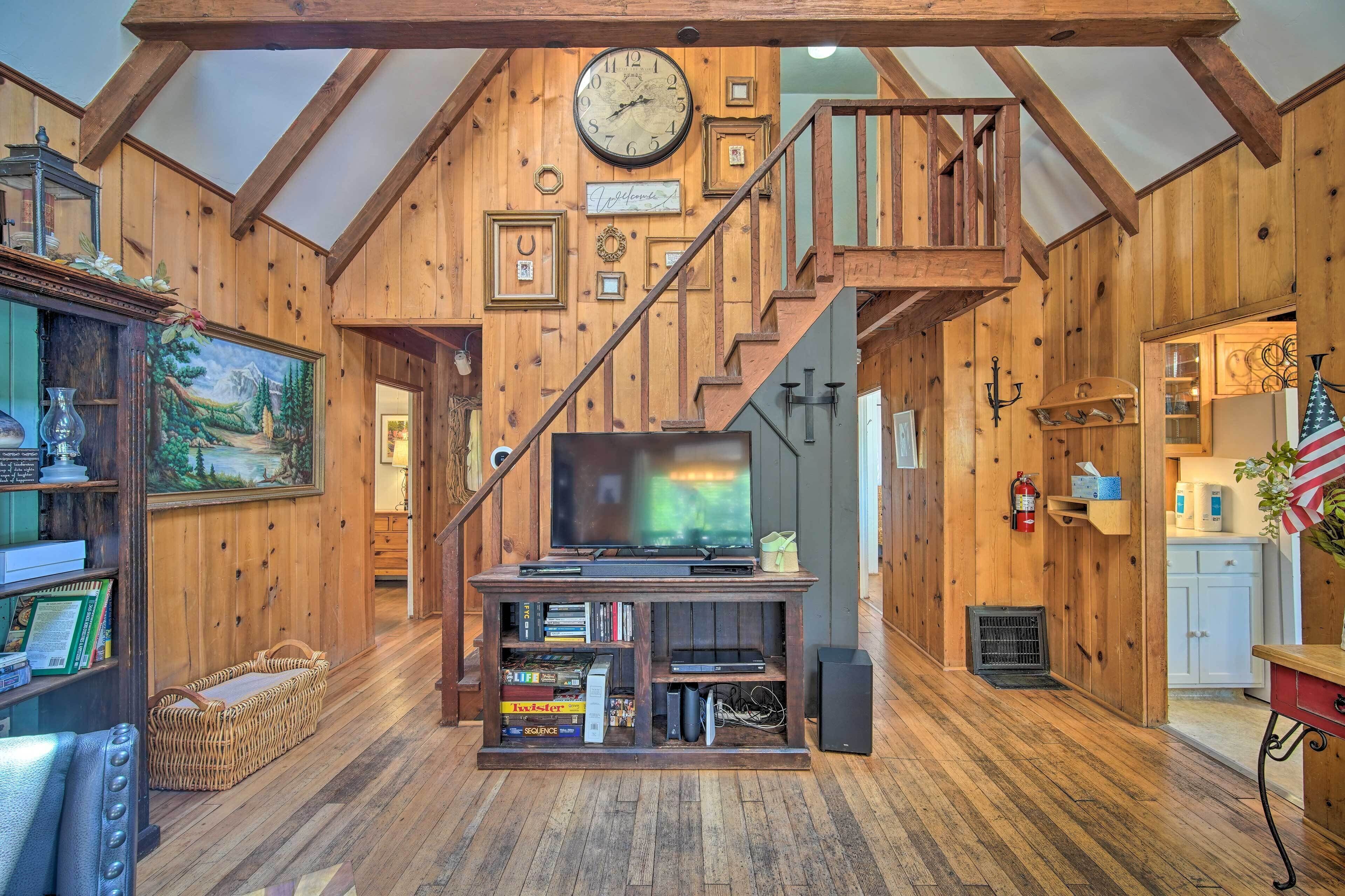 A wooden interior with a TV, books, and a staircase.