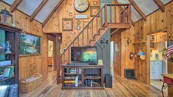 A wooden interior with a TV, books, and a staircase.