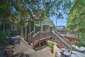 Ein überdachter Patio-Bereich mit Holzterrasse, Sitzgelegenheiten im Freien und einem kleinen Gebäude mit einer Tür.