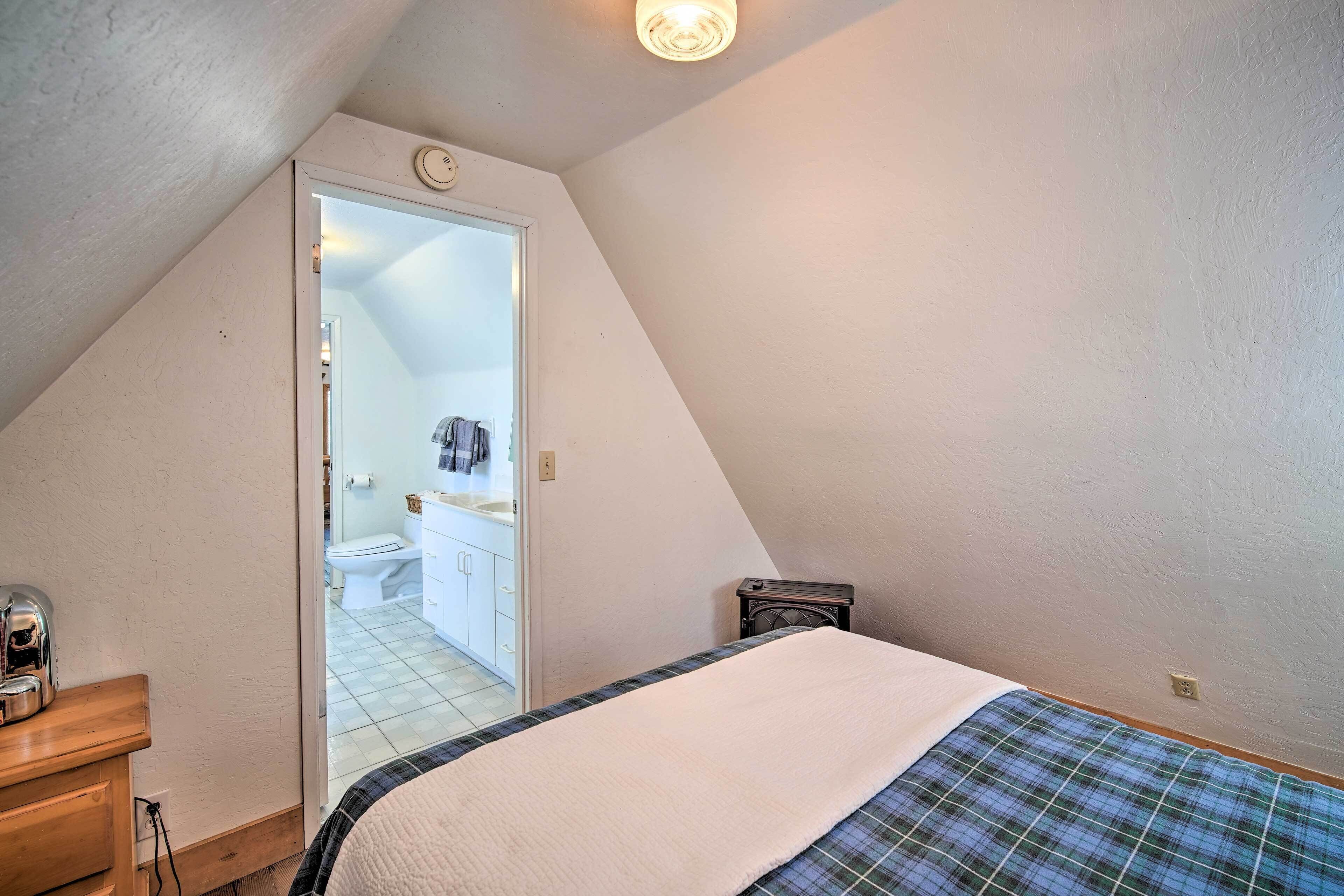 A bedroom with a bed, a dresser, and a door leading to a bathroom.