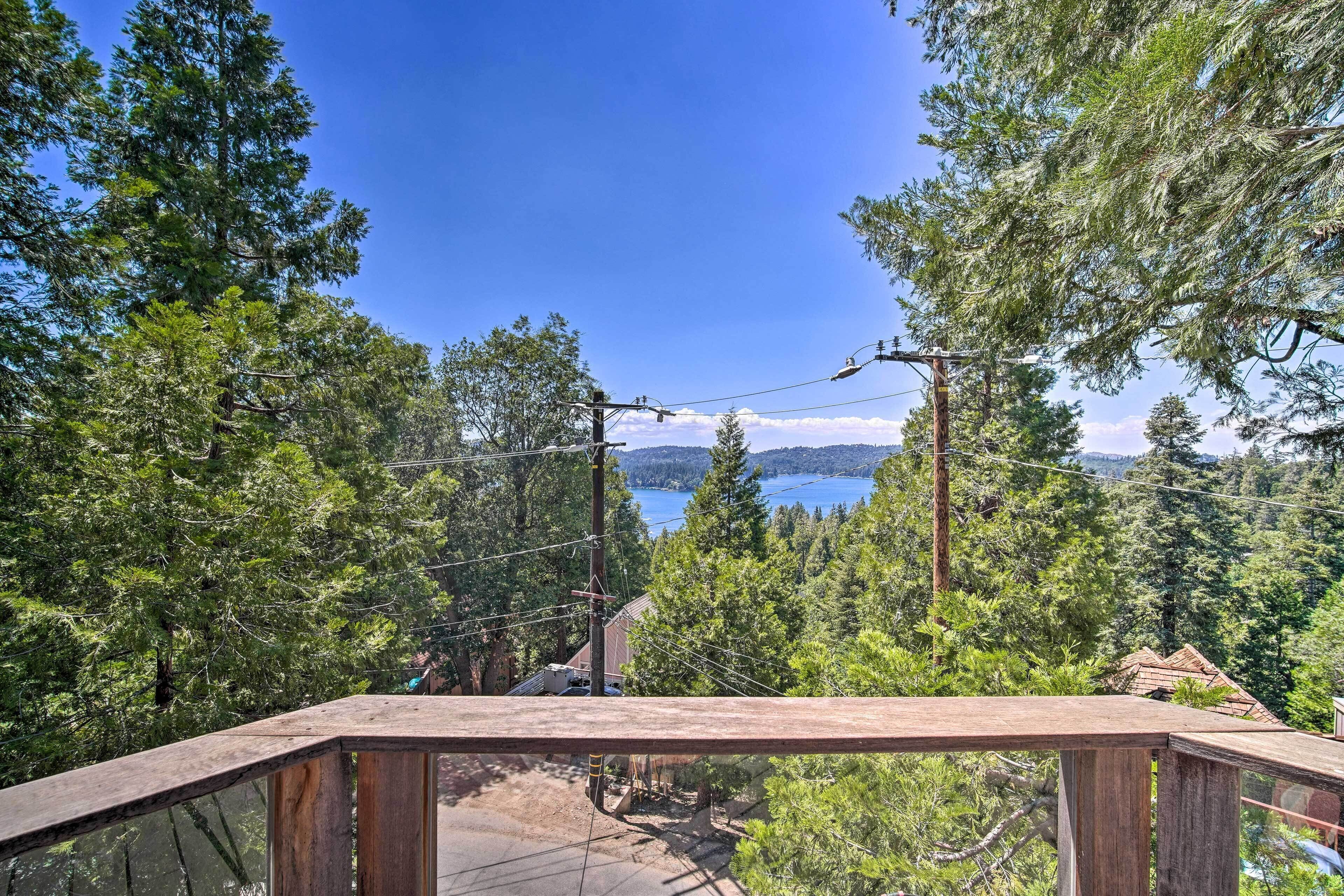 A wooden deck with a clear view of a lake and surrounding trees.