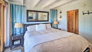 A bedroom with a large bed, two bedside tables, a mirror, and a wooden door. - Lakeview Lodge Fit for Groups < 1 Mile to Lake! (Cedar Glen)