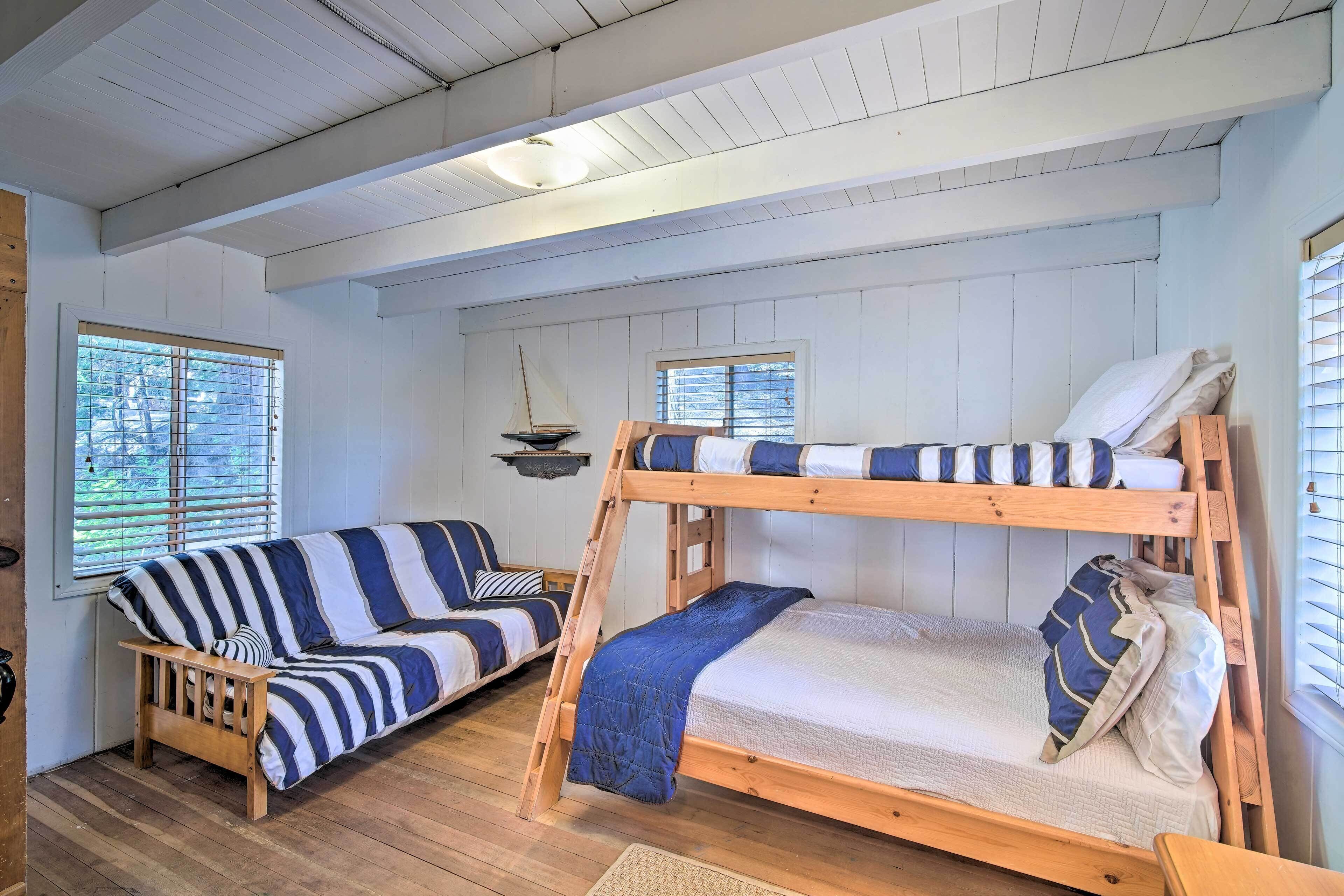 A room with a bunk bed, a striped sofa, and a small table.
