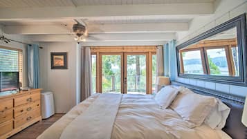 A bedroom with a large bed, wooden dresser, and a ceiling fan.