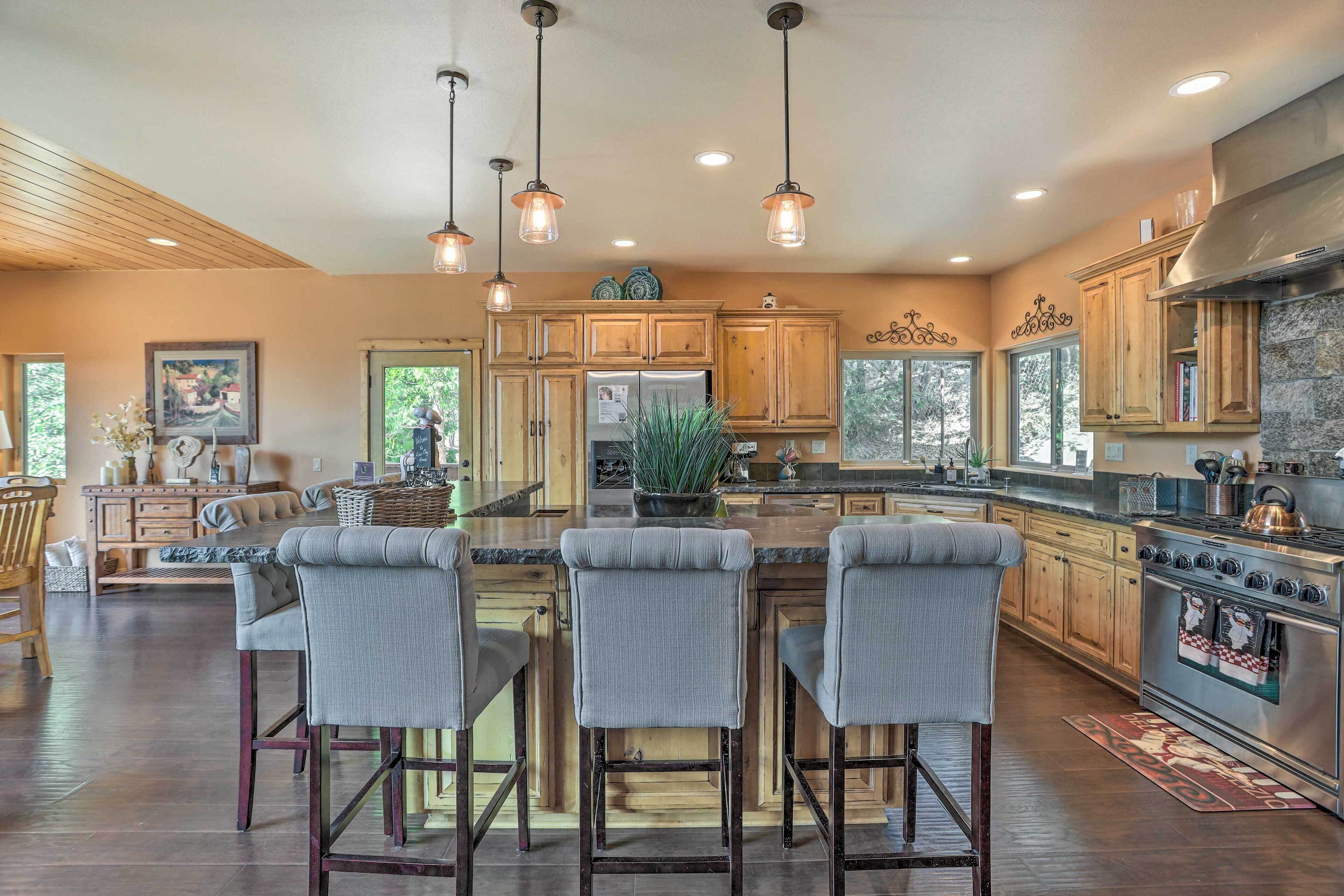A spacious kitchen with wooden cabinets, a central island with bar stools, and a large stove.