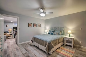 Un dormitorio con cama, lámparas de noche, ventilador de techo y alfombra a rayas.