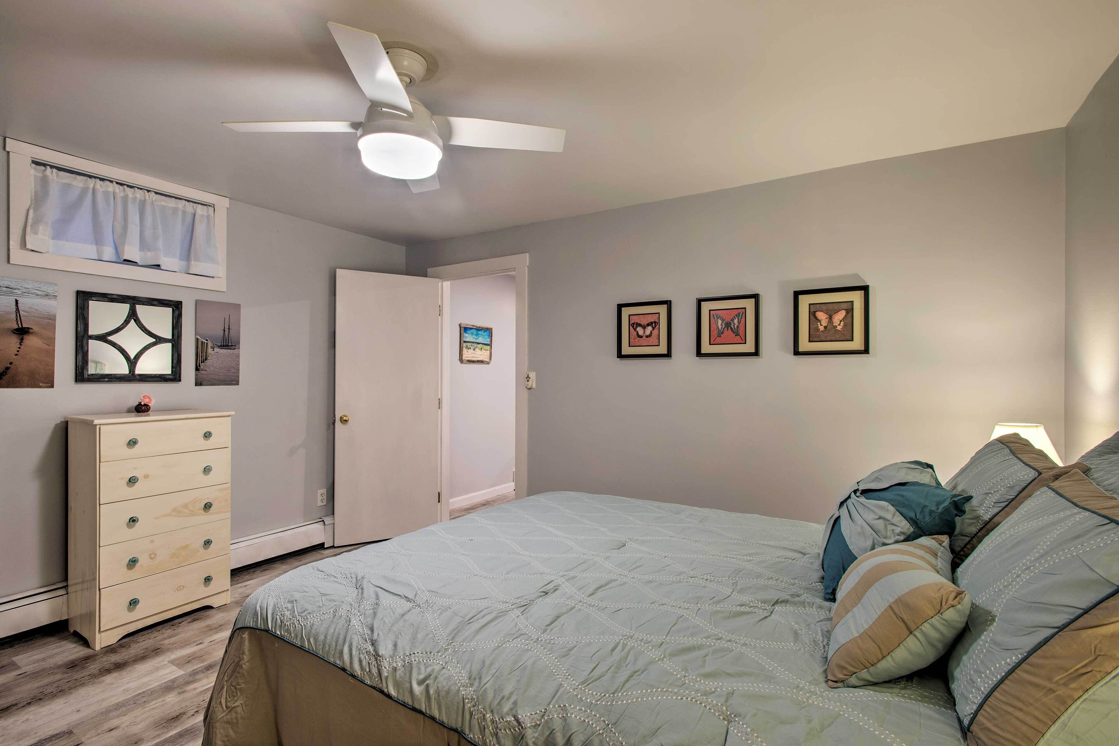 Ein Schlafzimmer mit Bett, Schminktisch, Deckenventilator und Wandbildern.