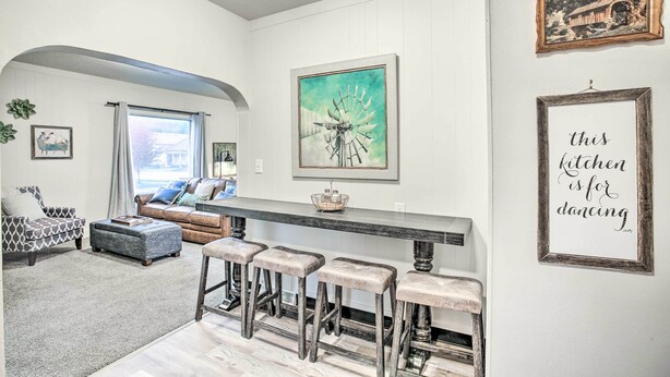 A kitchen with a long counter, bar stools, and a wall with a windmill painting and a sign saying "this kitchen is for dancing." - High-end & Homey Family Abode: Walk Downtown! (Coeur d'Alene)