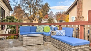 A covered outdoor seating area with wicker furniture and blue cushions, overlooking a residential neighborhood. - High-end & Homey Family Abode: Walk Downtown! (Coeur d'Alene)