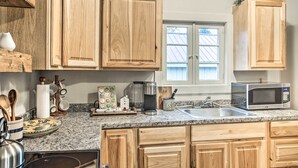 A kitchen with wooden cabinets, granite countertops, a stainless steel sink, and a microwave. - High-end & Homey Family Abode: Walk Downtown! (Coeur d'Alene)
