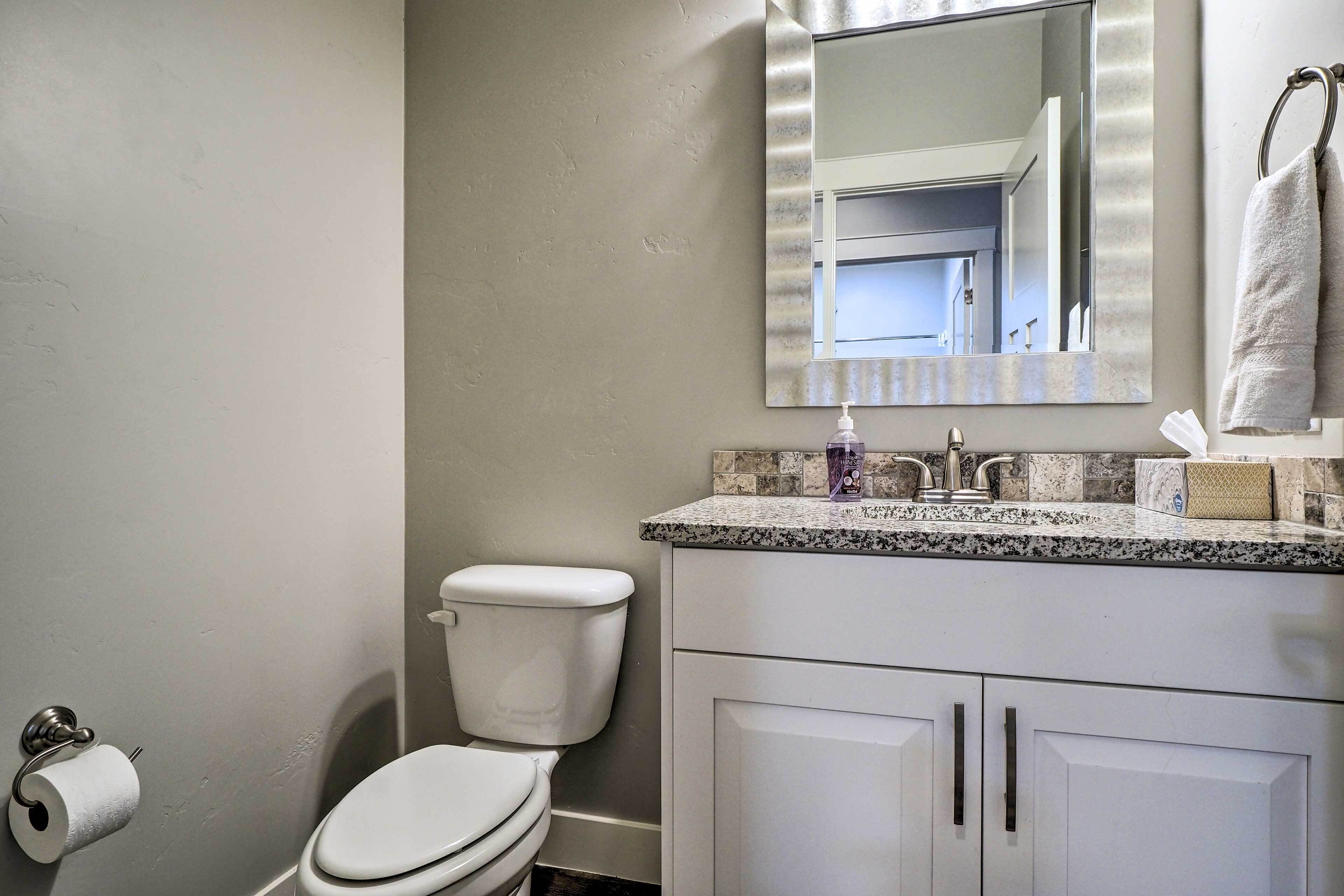 A bathroom with a toilet, sink, mirror, and towel rack.