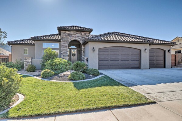 A two-story house with a stone facade, a front garage, and a well-maintained lawn.