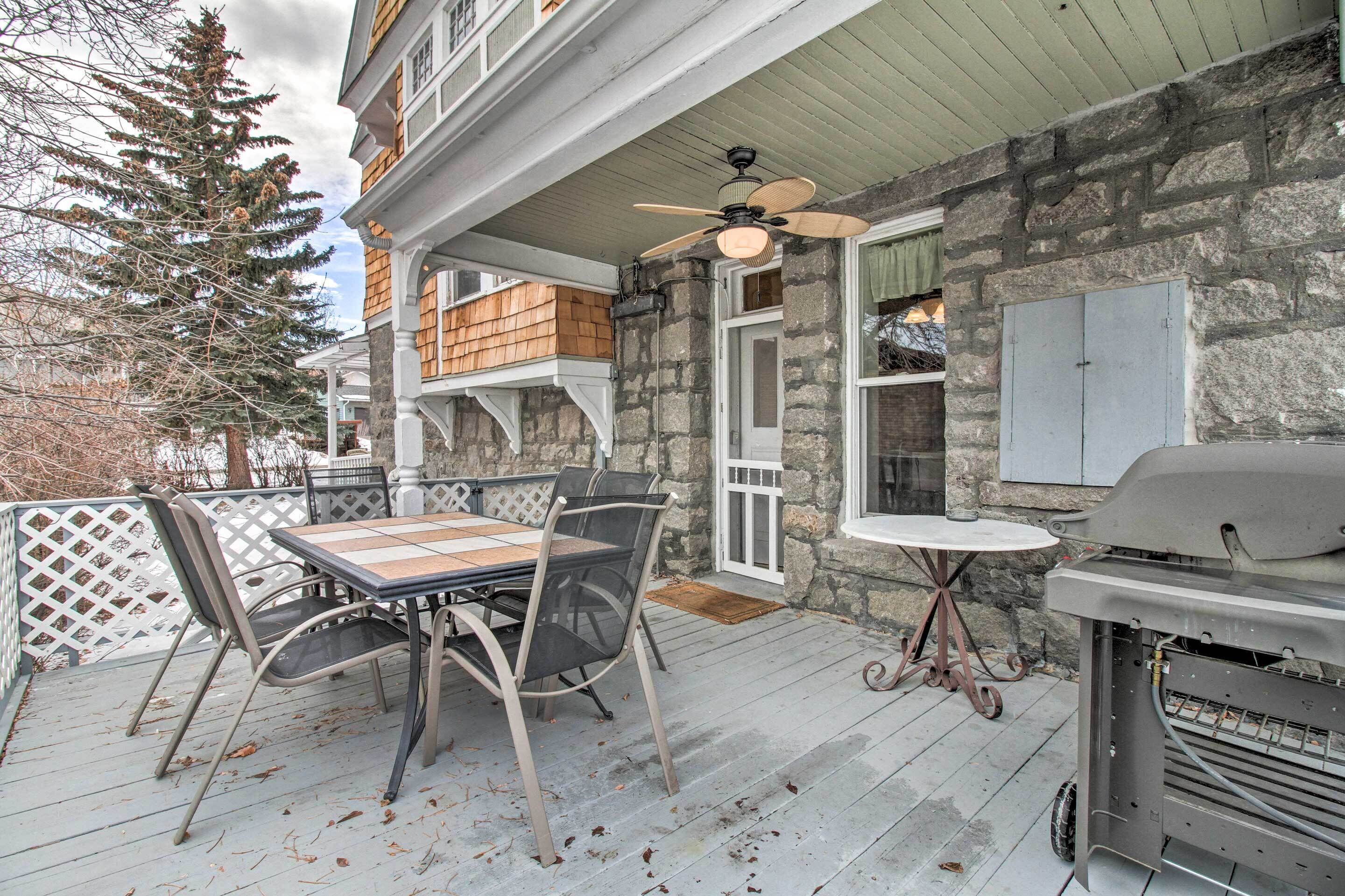 An outdoor patio with a table and chairs, a ceiling fan, and a barbecue grill.