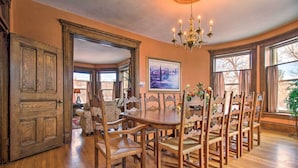 Comedor con mesa y sillas de madera, candelabro y ventana grande con vistas.