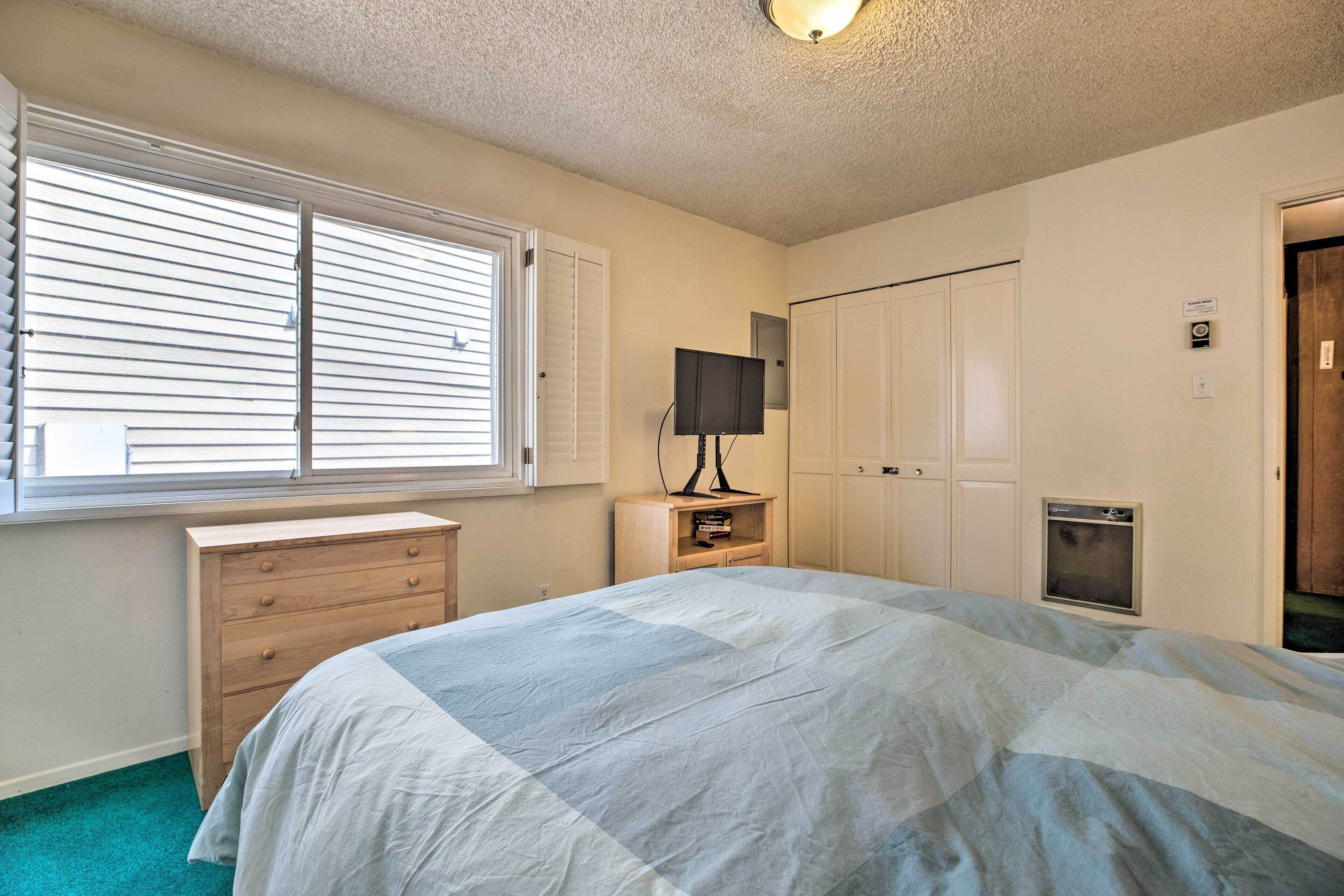 Une chambre à coucher comprenant un lit, une commode, un téléviseur et une armoire.