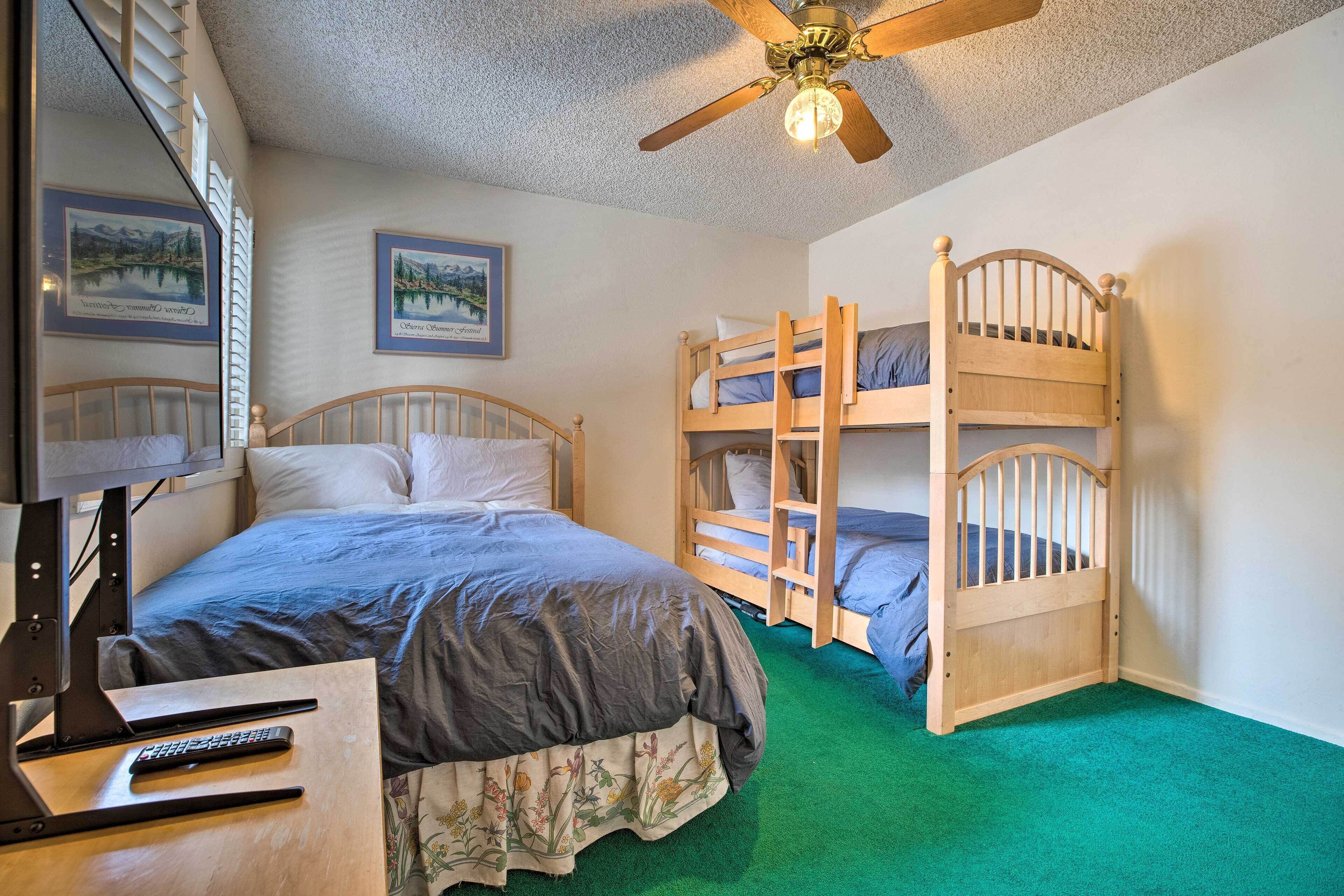 A bedroom with bunk beds, a ceiling fan, and a bed with a TV stand.