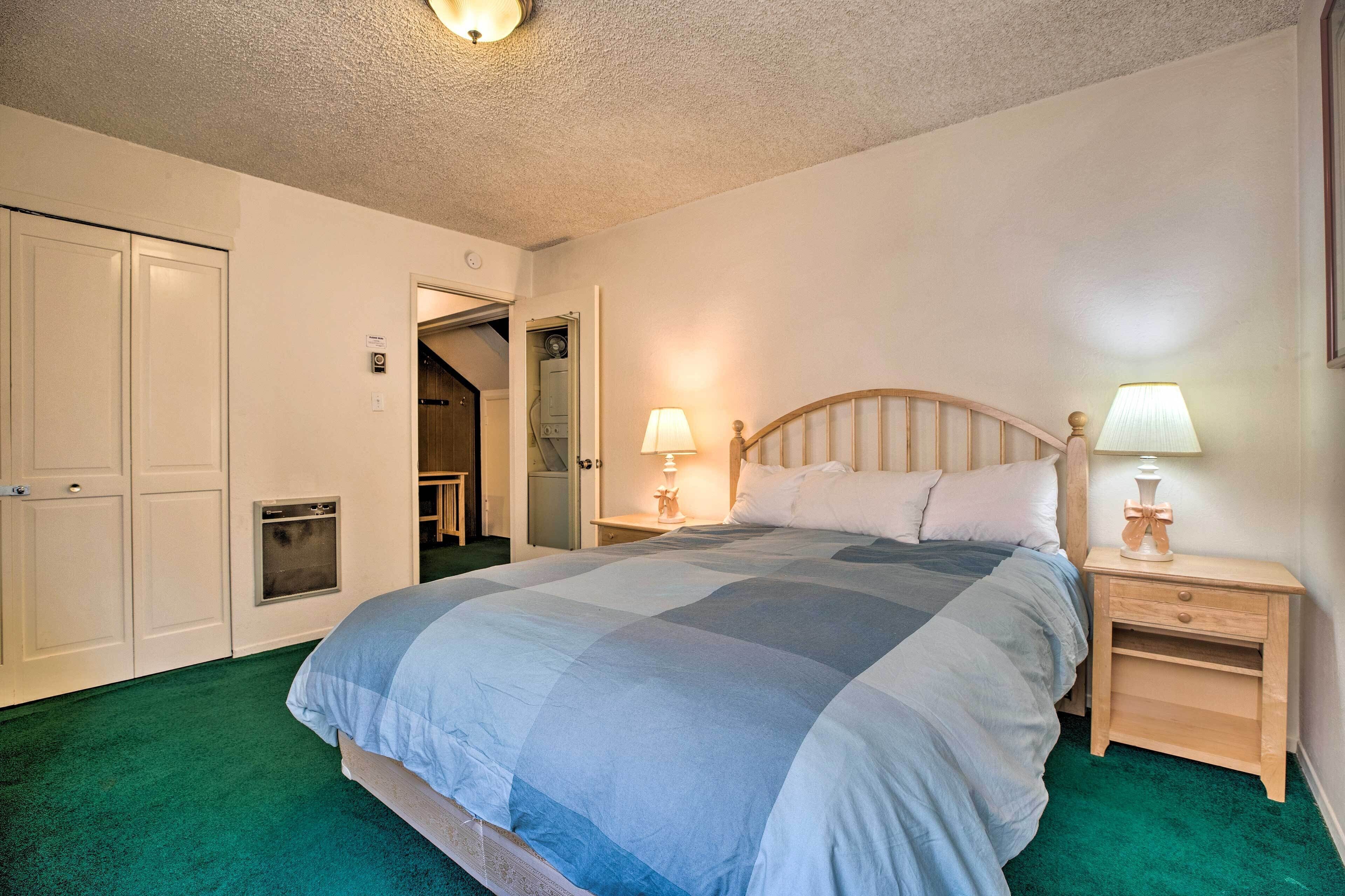 A bedroom with a bed, two bedside tables with lamps, a wardrobe, and a door leading to a bathroom.