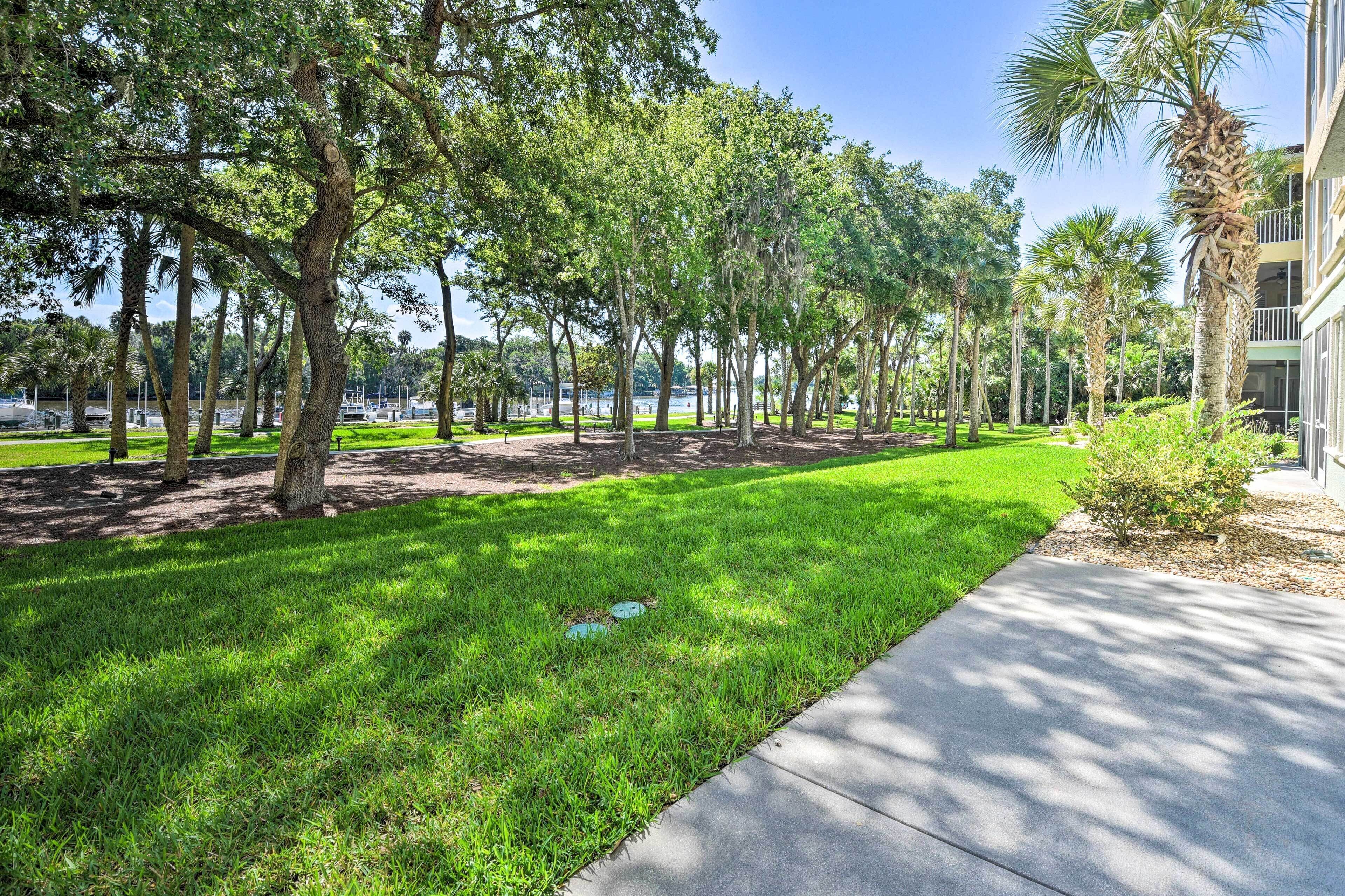 A well-maintained grassy area with trees and a building in the background.
