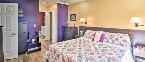 A bedroom with a large bed, a ceiling fan, a dresser, and a nightstand.
