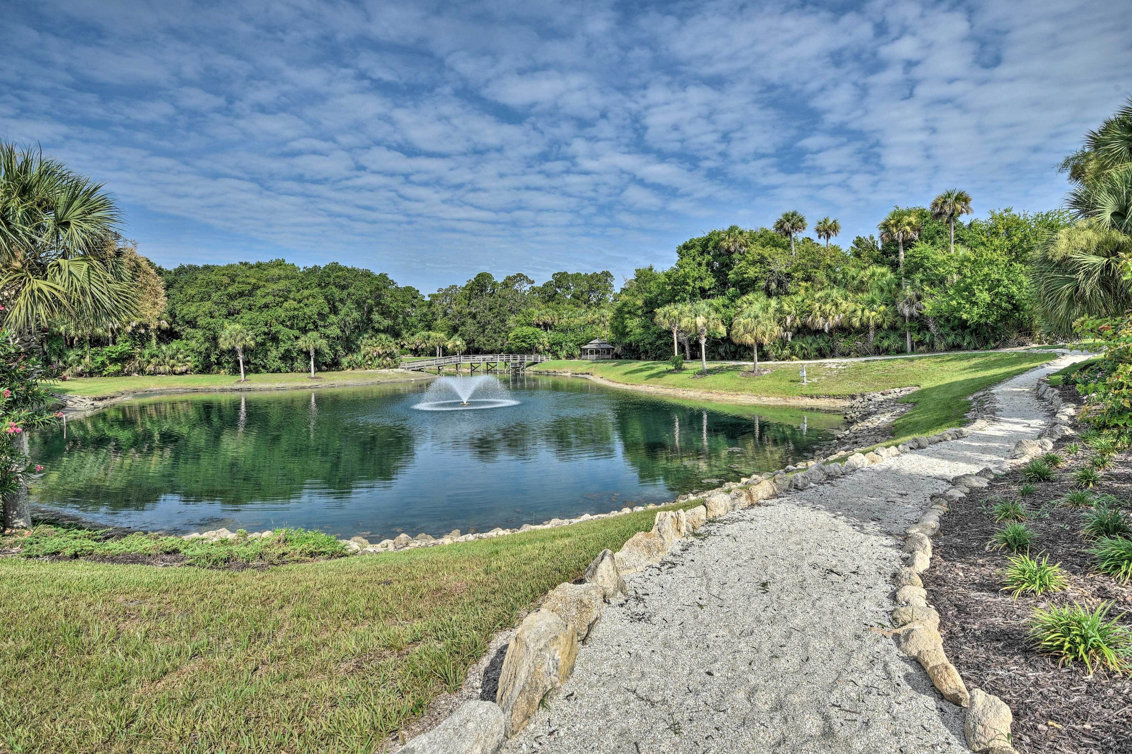 Un parco con uno stagno, un ponte di legno e un vialetto in pietra.