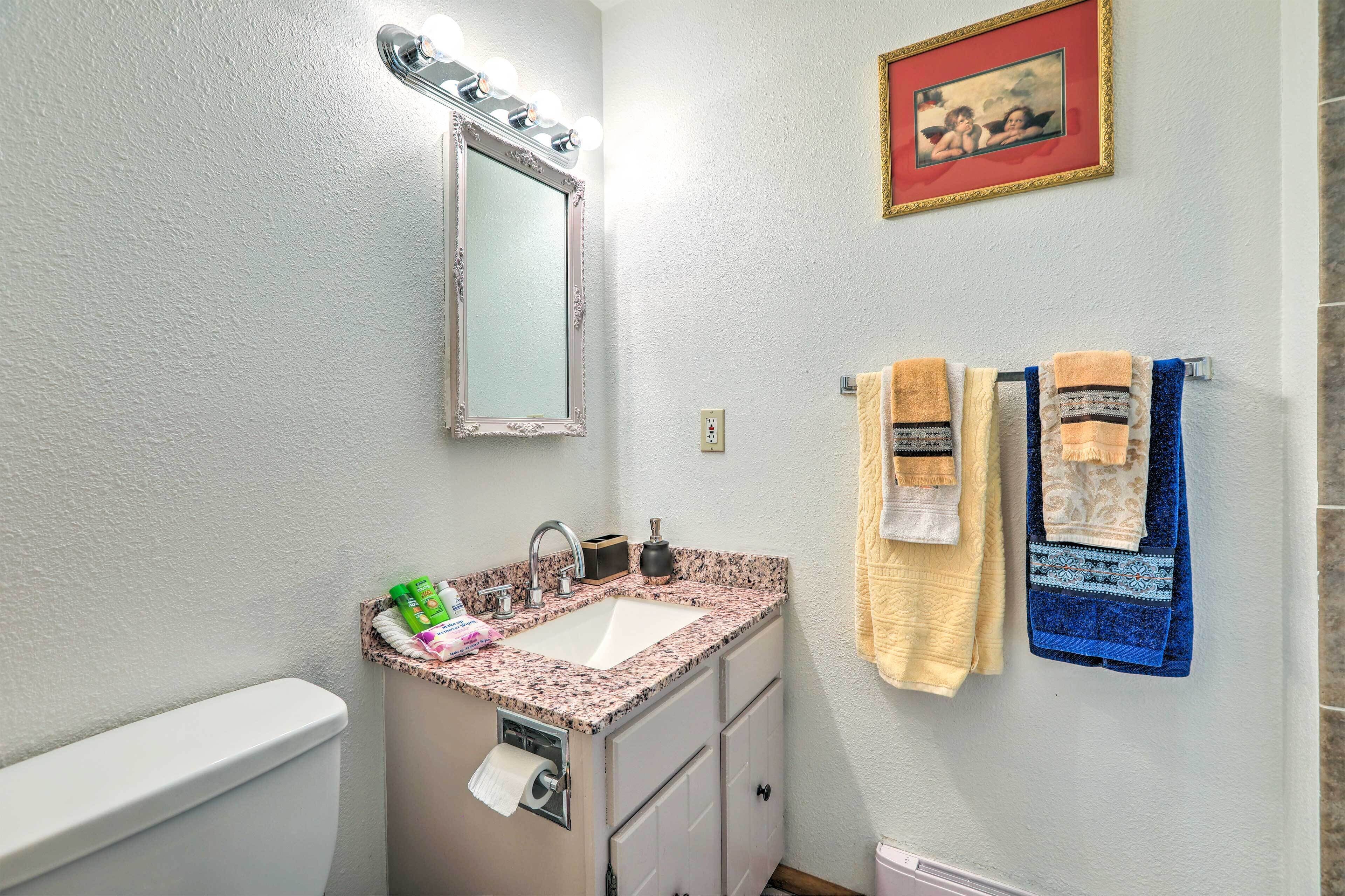 Une salle de bain équipée d’un lavabo, d’un miroir, d’un porte-serviettes et d’un tableau encadré au mur.