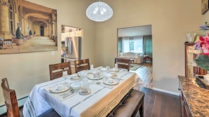 A dining area with a long table set for a meal, a chandelier, and a large painting on the wall. - Scenic Woodland Park Cottage w/ Deck + Grill! (Woodland Park)