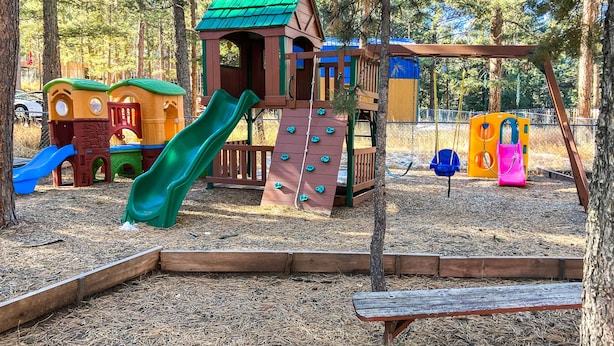 A playground with a wooden playhouse, slides, and climbing structures. - Scenic Woodland Park Cottage w/ Deck + Grill! (Woodland Park)