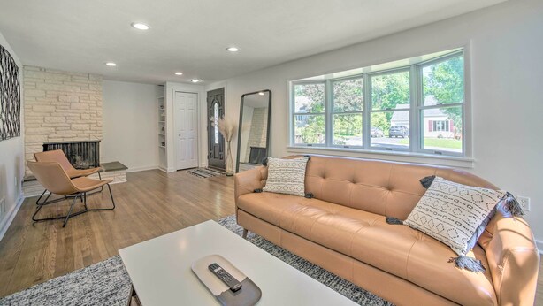 A modern living room with a leather sofa, a white coffee table, and a fireplace. - Artsy Upstate Getaway w/ Huge Private Yard! (Whitesboro)