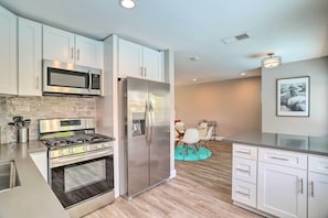 A modern kitchen with white cabinets, stainless steel appliances, and a dining area with a round table and chairs.