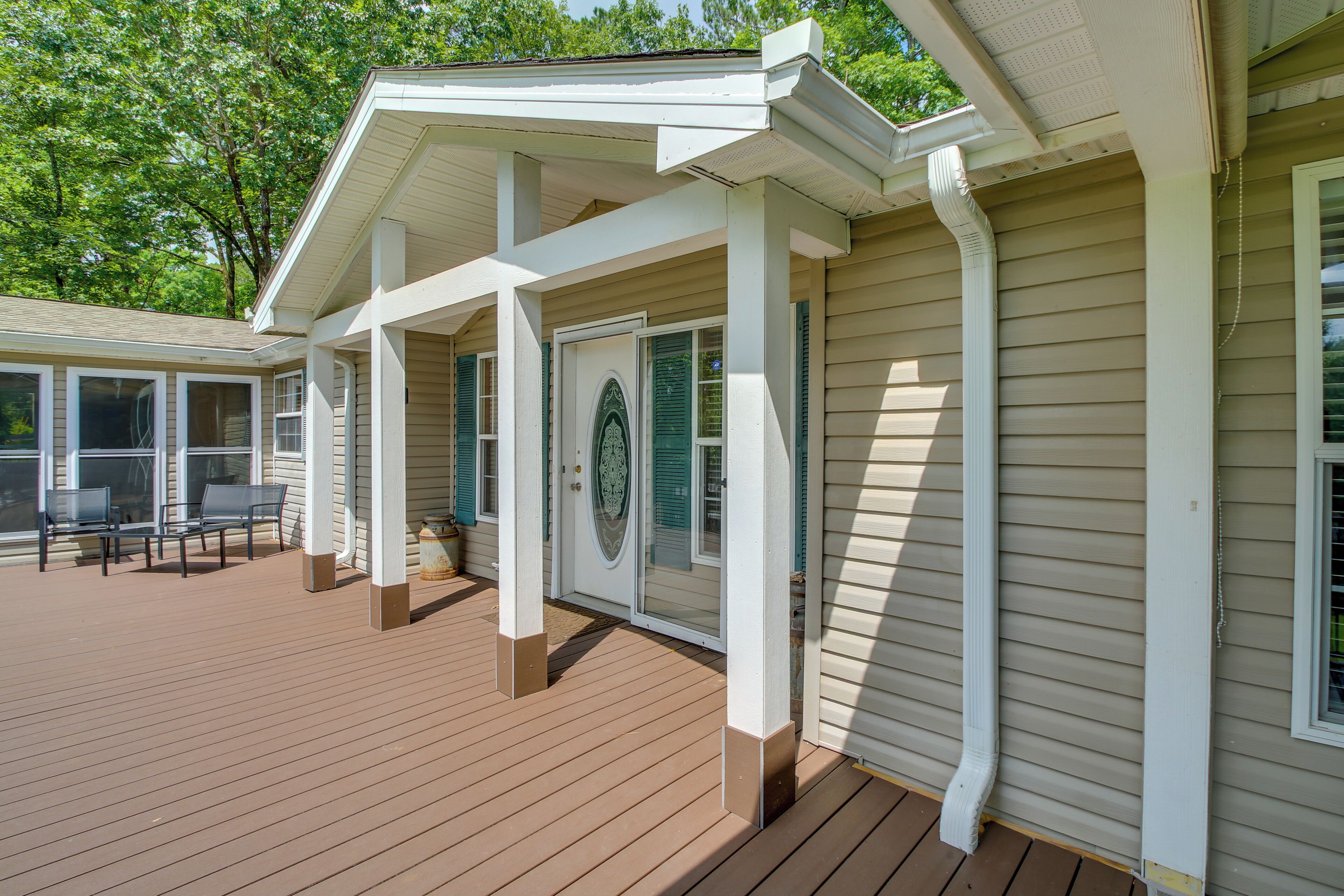 Una terraza techada con mobiliario exterior y una puerta con panel de vidrio decorativo.