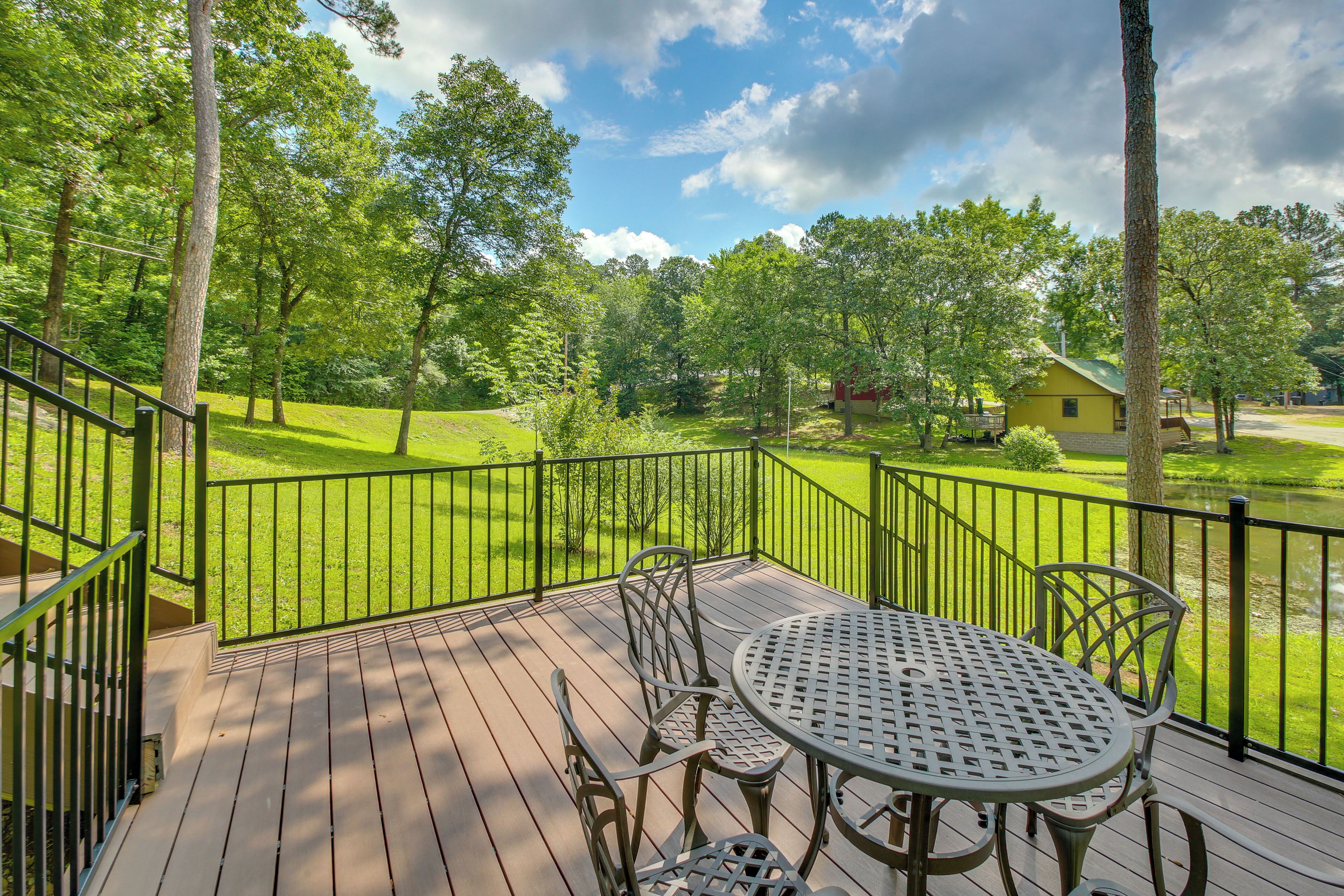 A deck with a table and chairs, surrounded by a green lawn and trees.