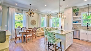 A spacious kitchen with wooden flooring, white cabinetry, and a central island. There are multiple windows providing natural light, and a ceiling fan is visible.