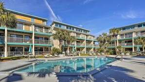 A hotel with a swimming pool, multiple balconies, and palm trees. - Oceanfront Panama City Beach Condo w/ Balcony! (Panama City Beach)