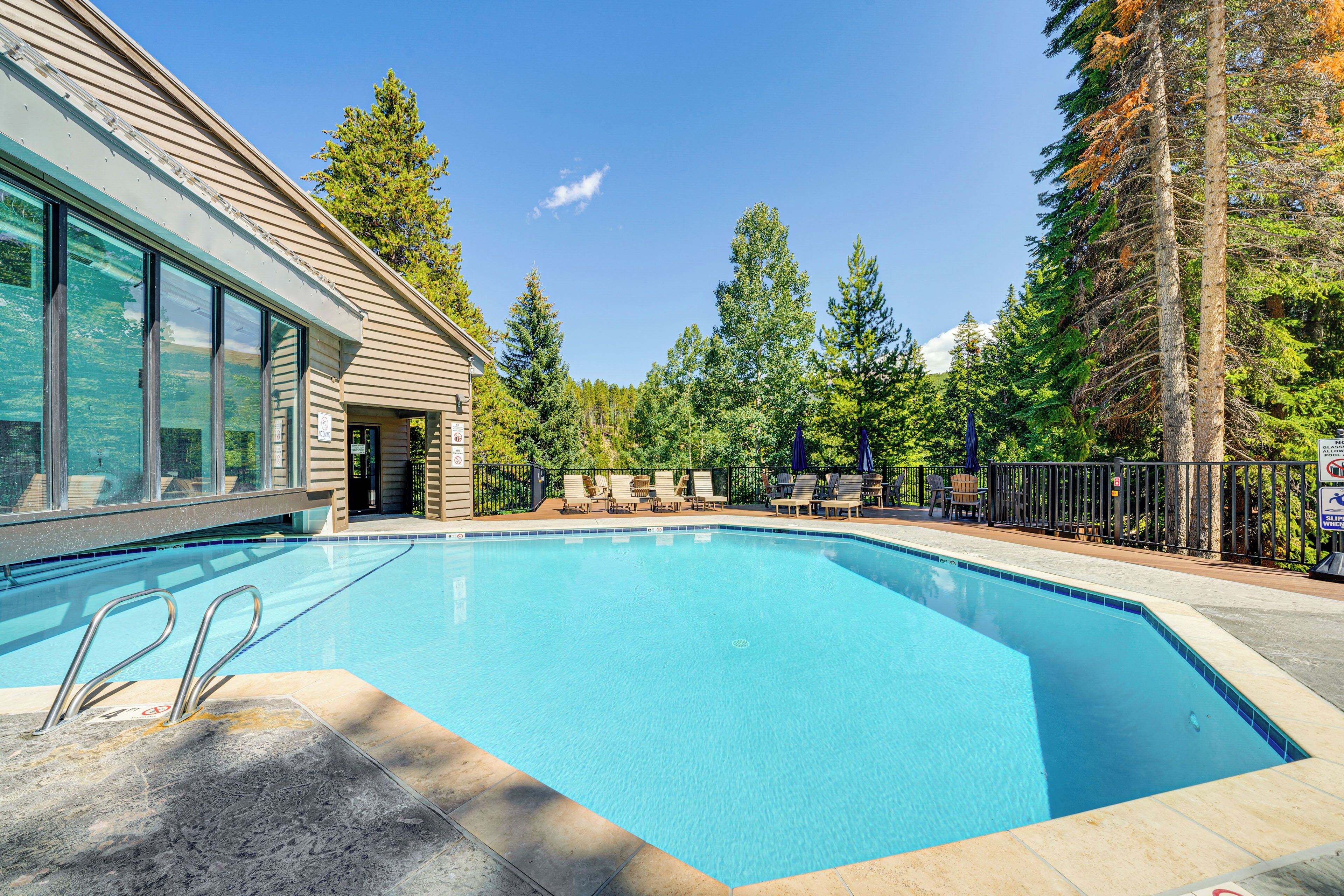 A swimming pool with lounge chairs and a building with large windows.