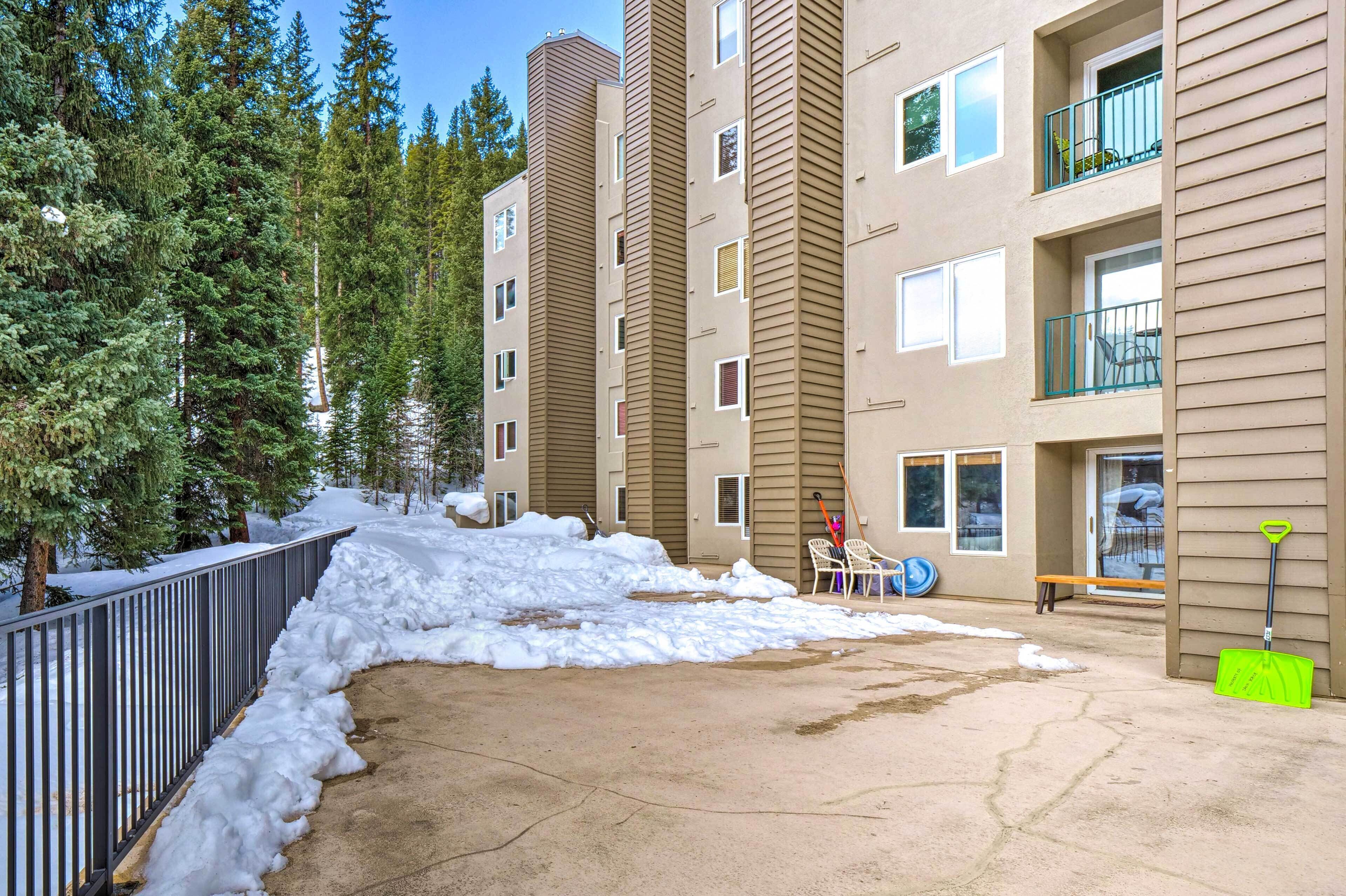 Un edificio residencial de varios pisos con suelo cubierto de nieve y una valla metálica.
