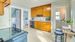 A modern kitchen with wooden cabinets, a dishwasher, and a dining area with stools. - 'ania's Retreat' w/ Deck: Walk to Lake Michigan! (Two Rivers)