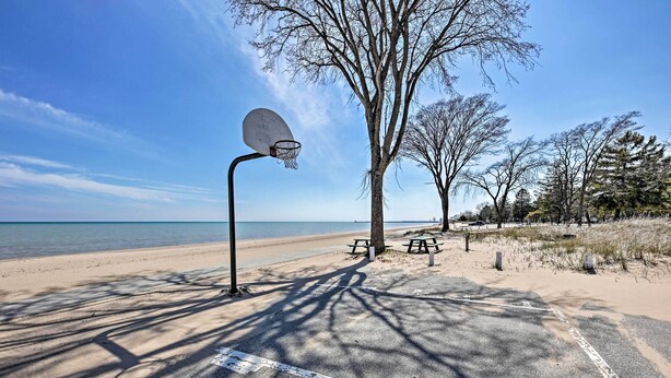 A basketball court with a hoop, picnic tables, and trees near a beach. - 'ania's Retreat' w/ Deck: Walk to Lake Michigan! (Two Rivers)