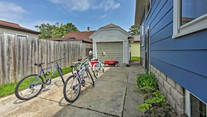 A residential backyard with a wooden fence, a garage, and bicycles parked on the driveway. - 'aj's Retreat' w/ Deck: Walk to Lake Michigan! (Two Rivers)