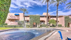 A pool with a fountain, surrounded by palm trees and a building with a blue awning. - Condo w/ Patio, Walk to Downtown Palm Springs! (Palm Springs)