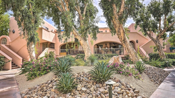 A courtyard with a stone pathway, palm trees, and a building with arches and a balcony. - Condo w/ Patio, Walk to Downtown Palm Springs! (Palm Springs)