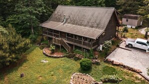 Eine Holzdiele mit Veranda und überdachter Terrasse, umgeben von gepflegtem Rasen und Bäumen.