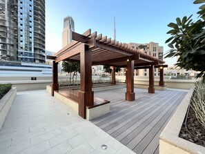 A wooden pergola structure on a rooftop terrace with a cityscape in the background.
