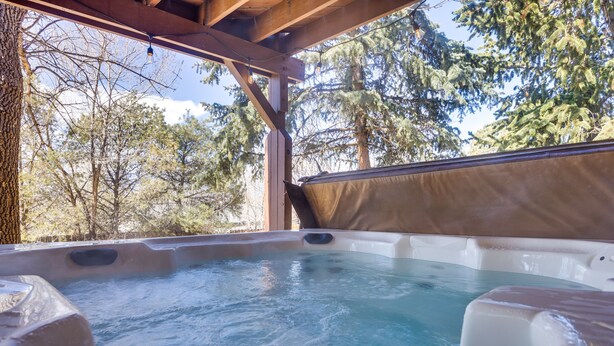 A hot tub with a view of trees and a wooden structure. - Lovely Colorado Springs Home: Mtn Views & Hot Tub! (Colorado Springs)