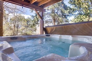Een hottub met uitzicht op bomen en een houten constructie.