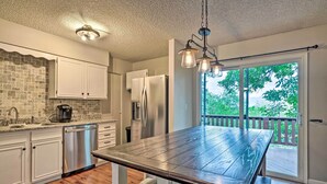 A modern kitchen with white cabinets, a stainless steel dishwasher, and a wooden table. - Lovely Colorado Springs Home: Mtn Views & Hot Tub! (Colorado Springs)
