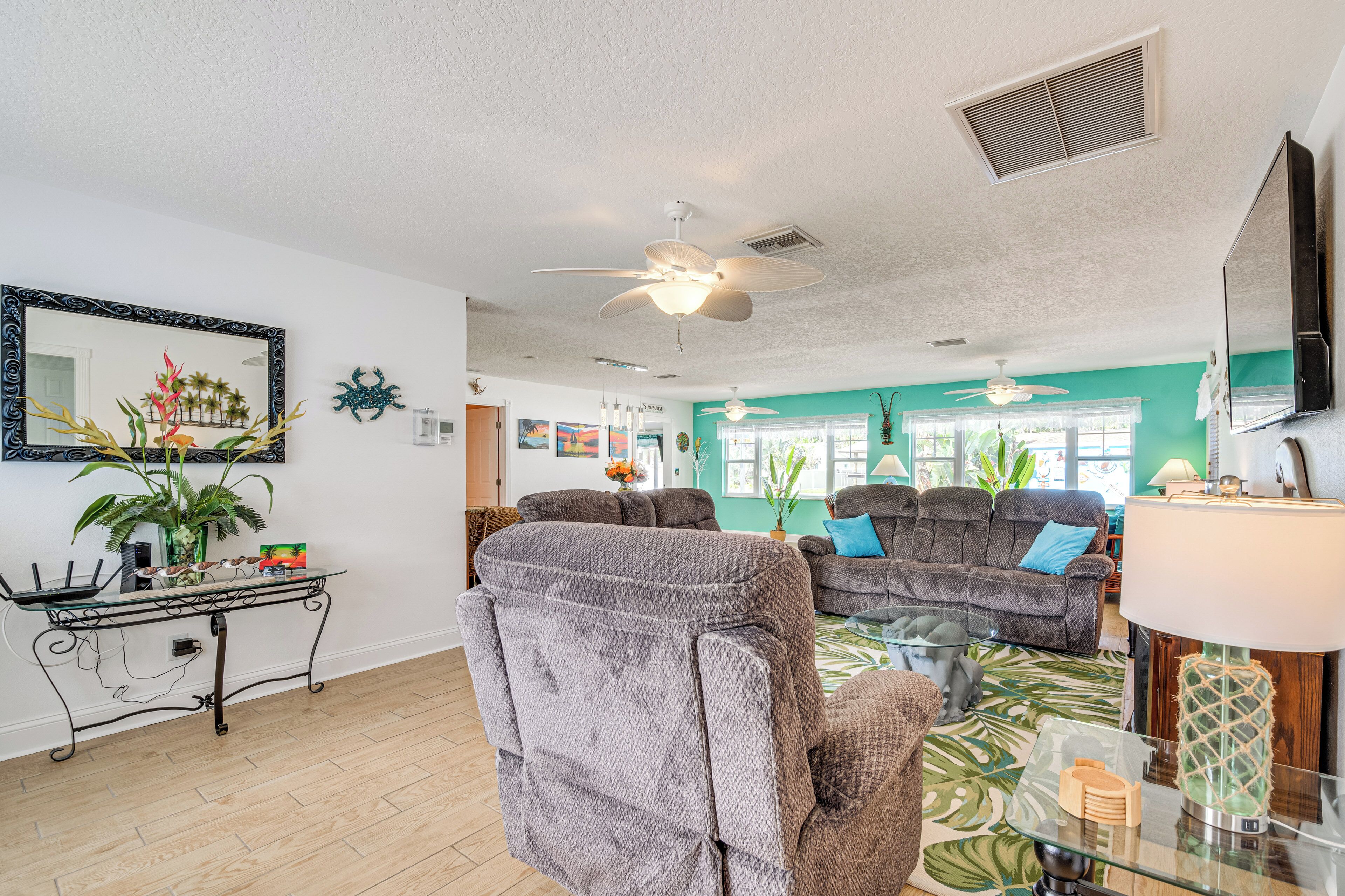 A living room with a ceiling fan, a large mirror, and a dining table with chairs.