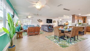 A spacious living area with a large ceiling fan, wicker furniture, and a kitchen with wooden cabinets. - Boat Dock & Kayaks: Canalfront Home in Homosassa (Homosassa)